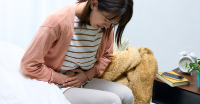 Seated woman doubled over in pain.