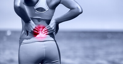 Woman clutching low back highlighted red to indicate pain.